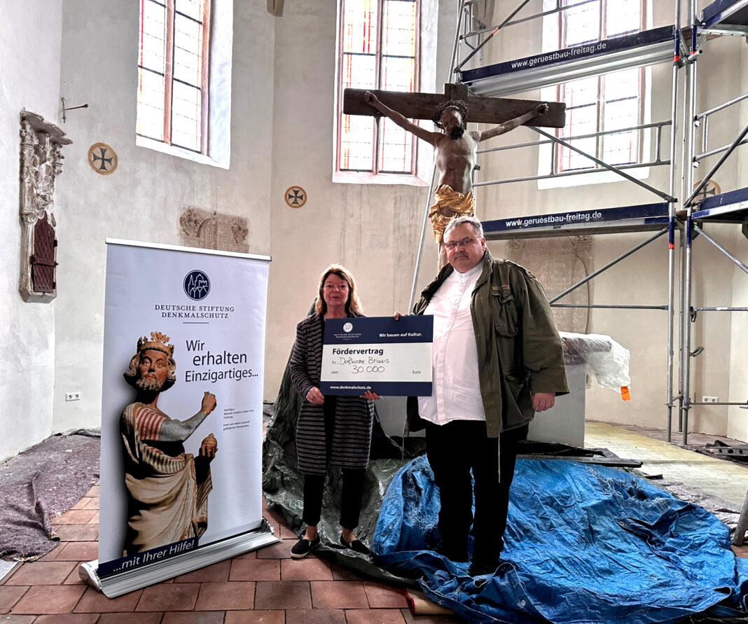 Angelika Dörrscheidt von der Deutschen Stiftung Denkmalschutz überreicht Pfarrer Matthias Taatz in der Kirche zu Brinnis den symbolischen Fördervertrag. Foto: Stephanie Bechert