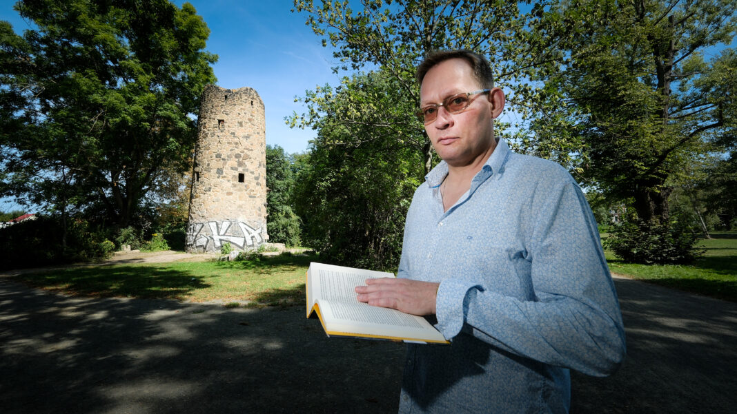 Der Leipziger Schriftsteller Clemens Meyer Im Güntz-Park in Leipzig Stötteritz. Im Hintergrund der Günz Turm, ein Überrest der Irren-, Heil- und Pflegeanstalt, die der Psychiater Günz im 19. Jahrhundert an diesem Ort betrieb. Im ersten Kapitel seines neuesten Buches spielt der Irrenarzt Güntz eine wichtige Rolle. Foto: Wolfgang Sens